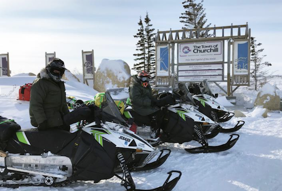 Rex Hibbert and Paul Dick pose by a sign March 6 welcoming visitors to Churchill, Man. (Photo courtesy of Rob Hallstrom)