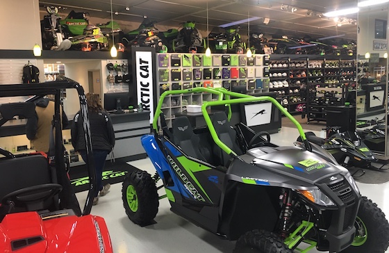 An SVX 450 snowbike and many other significant Arctic Cat snowmobile models line the ceilings near the parts counter